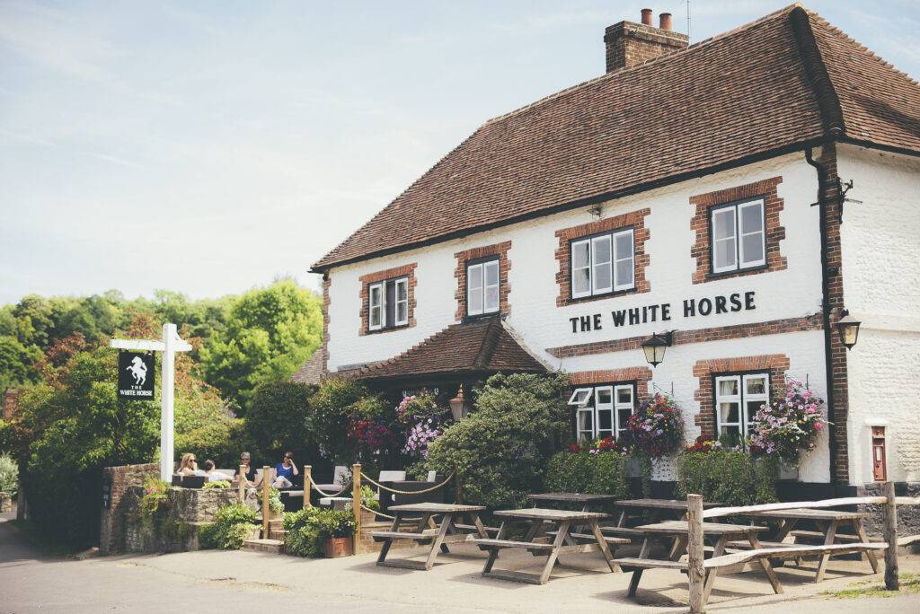 The outside of The White Horse Pub including benches and trees