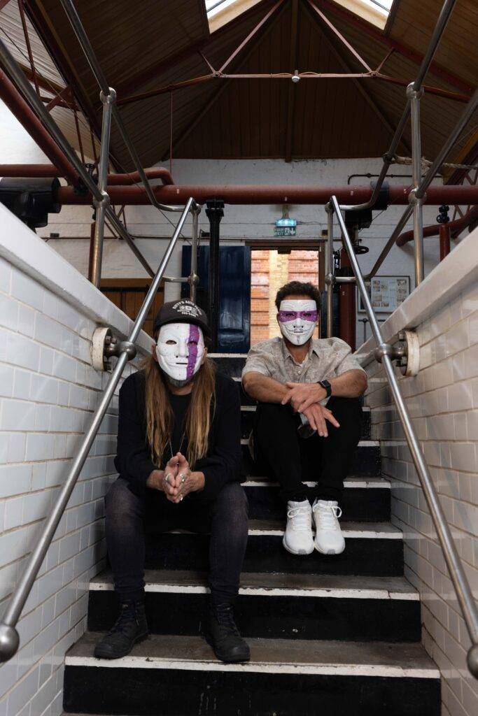 The Postman sitting on stairs with white masks on their faces